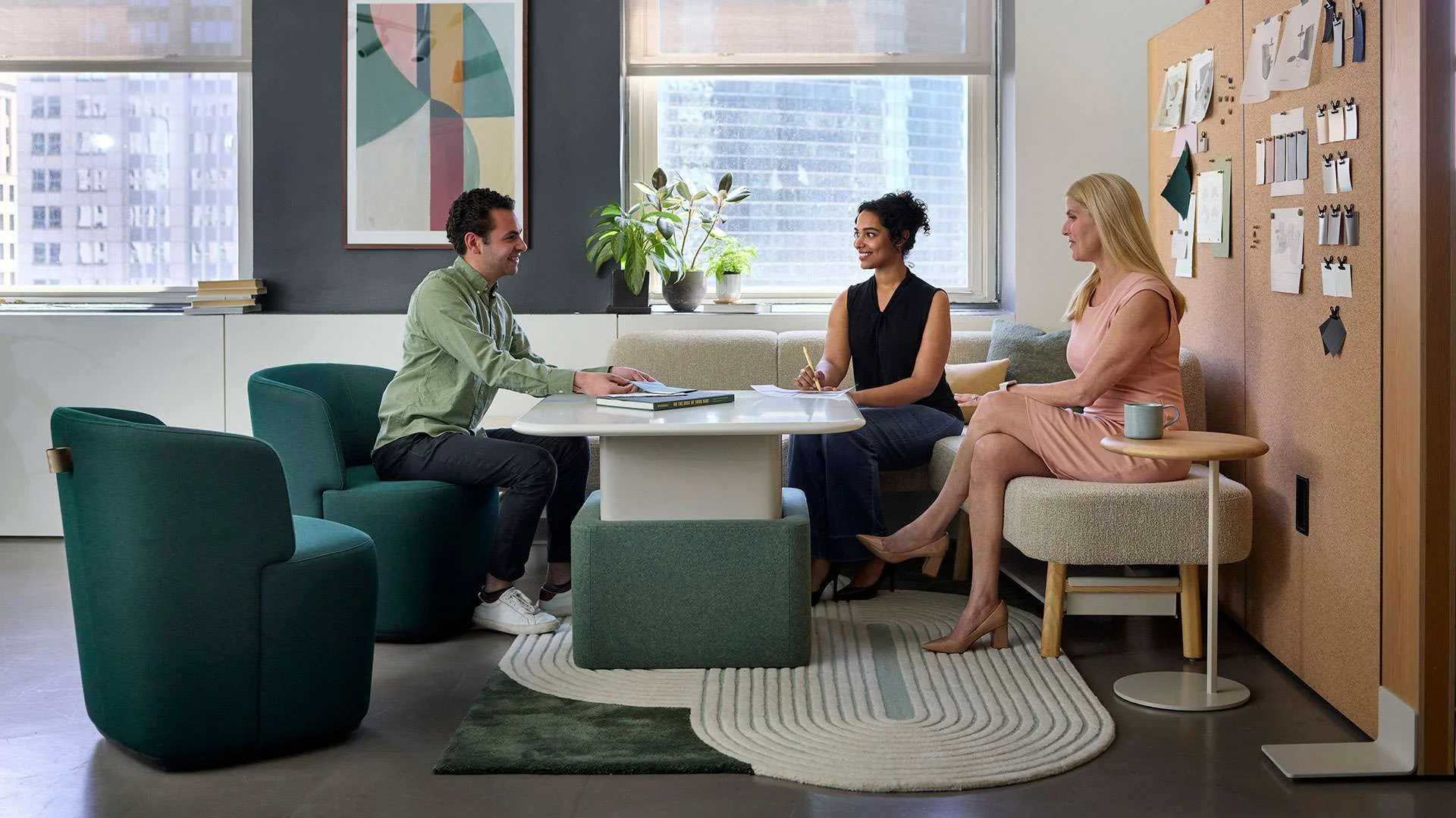An OFS-furnished collaboration space with three people meeting around a table